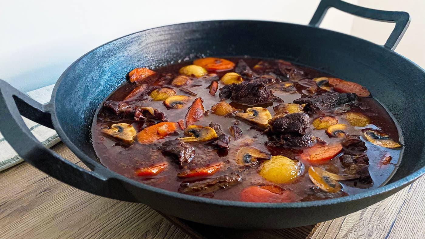Boeuf bourguignon av hjort i ei støypejernsgryte, med gulrot, sjampinjong og delikatesselauk i mørk raudvinssaus.